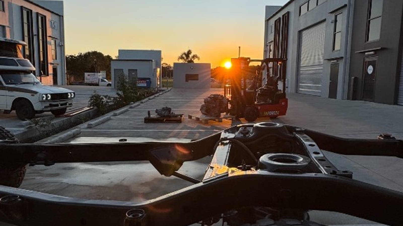 Bare 80 Series LandCruiser chassis at sunset, with the Chinook and V8 in the background