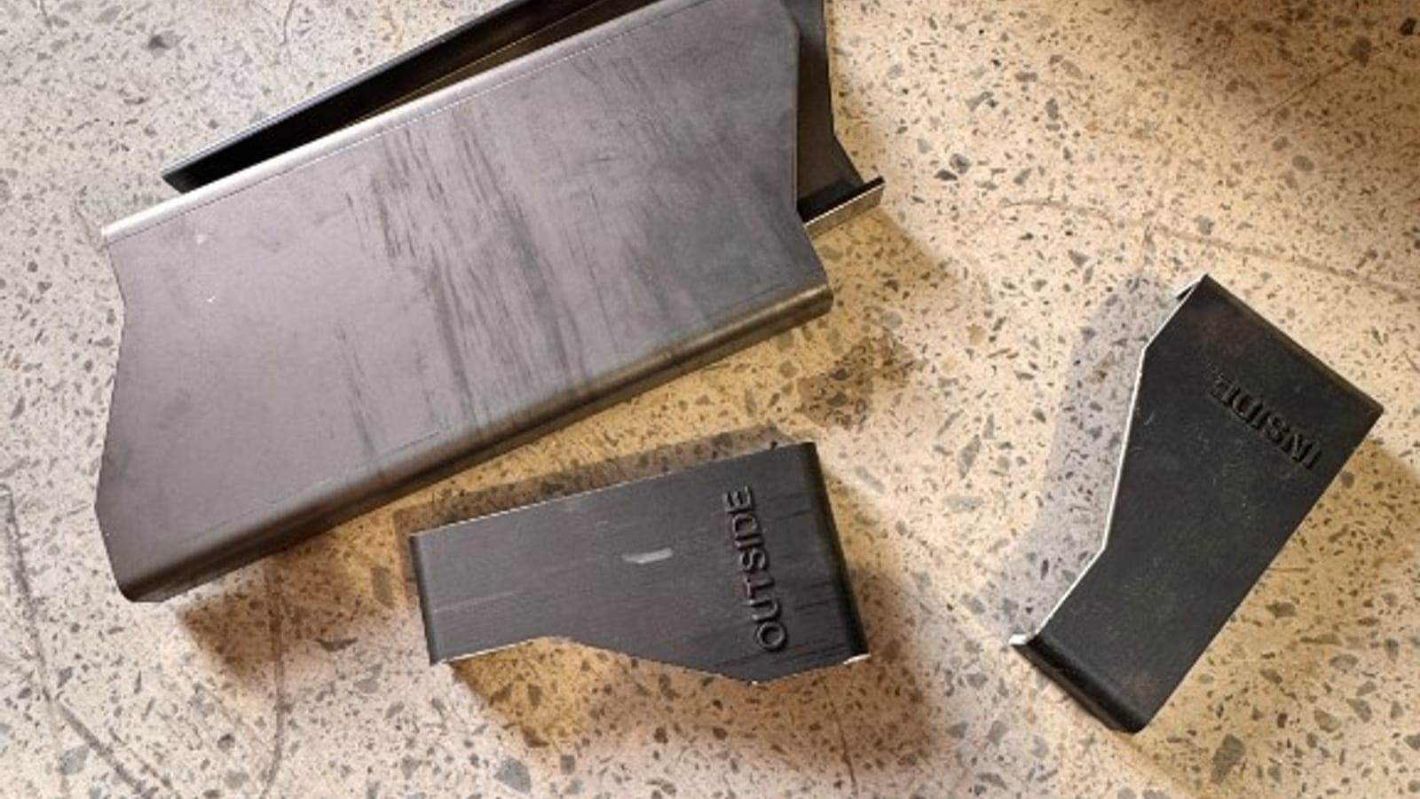 Custom fabricated chassis brackets marked inside and outside on the workshop floor